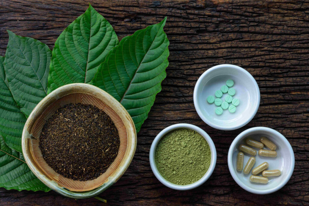 kratom products, edibles and leaves in a bowl on wooden table
